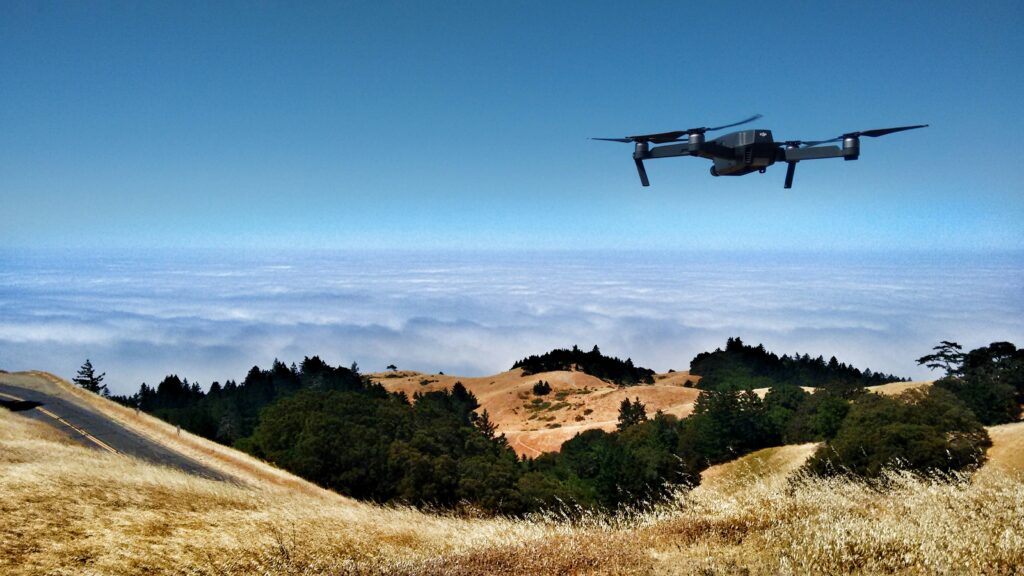 Photograph of drone flying across browned countryside